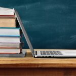Stack of books with laptop on table