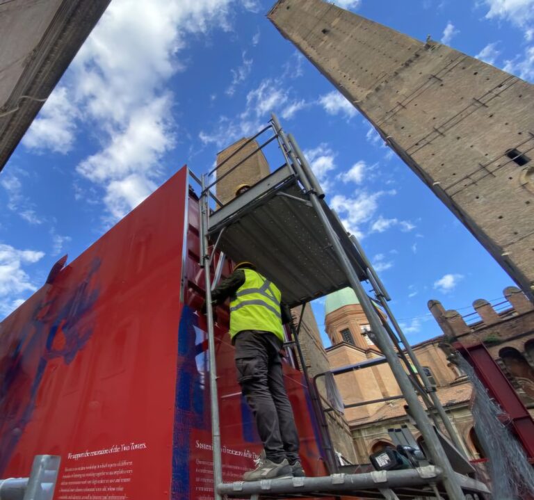 Una cintura rossoblu costellata di maxisagome museali riveste il cantiere della Garisenda 